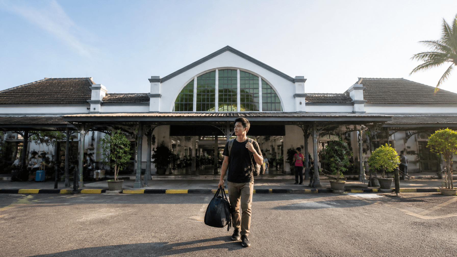 A cinematic shot of Purwokerto train station's modern yet classic architecture, with a traveler carr